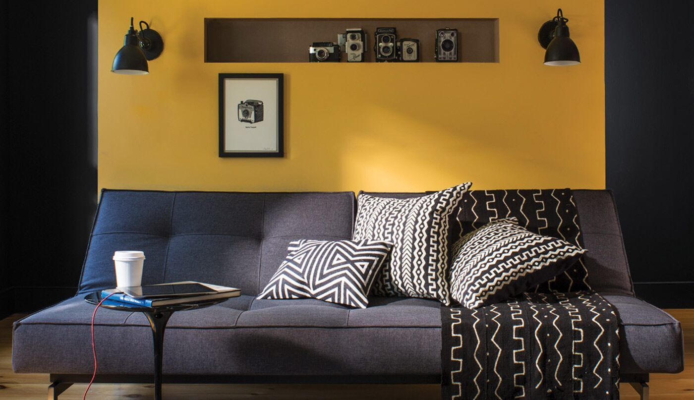 A living room with a gray couch and yellow walls