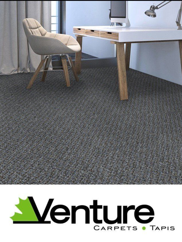 A room with a desk and chair and a venture carpet on the floor