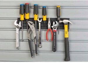 A bunch of tools are hanging on a rack on a wall.