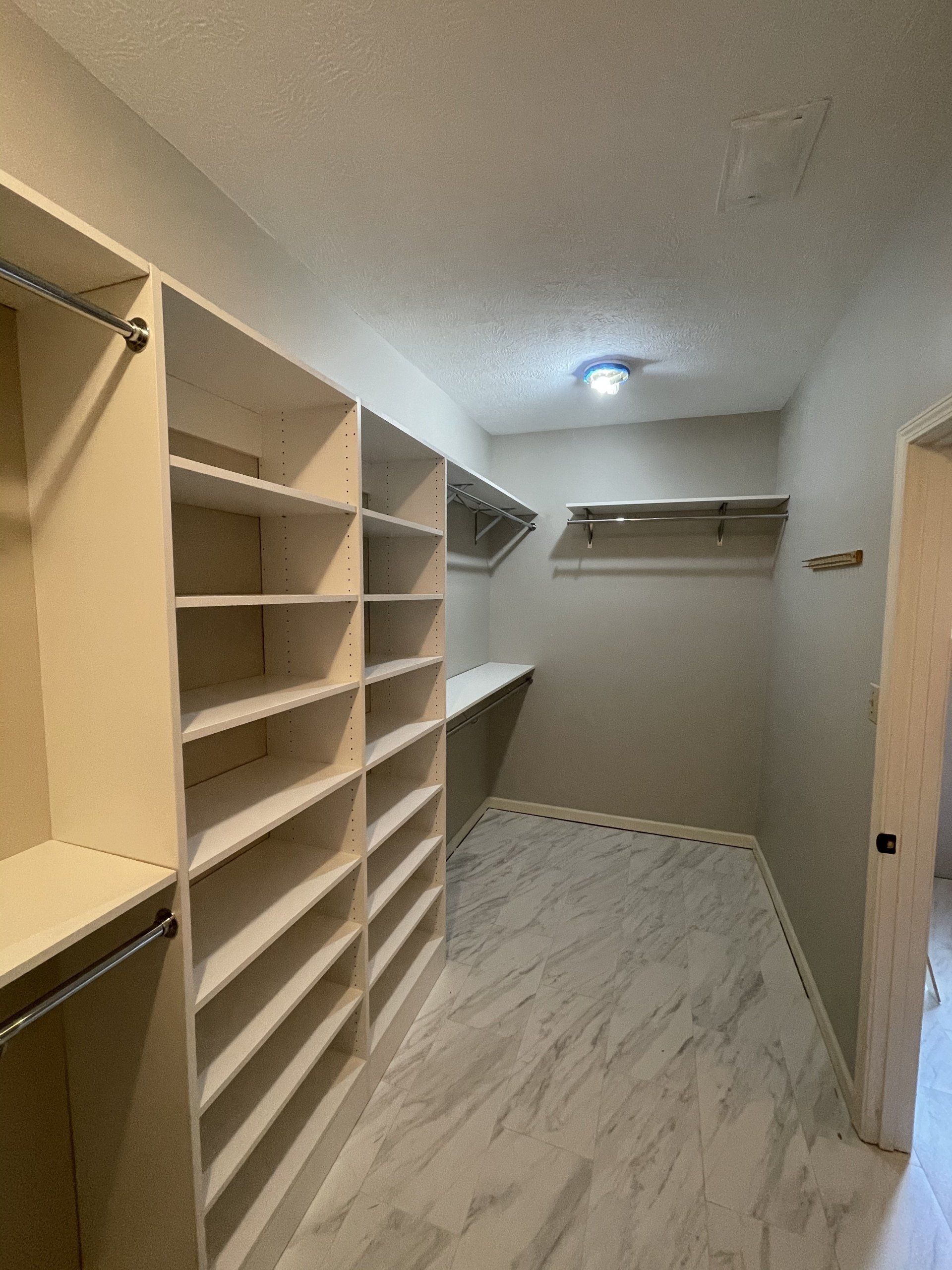 A walk in closet with lots of shelves and a door.