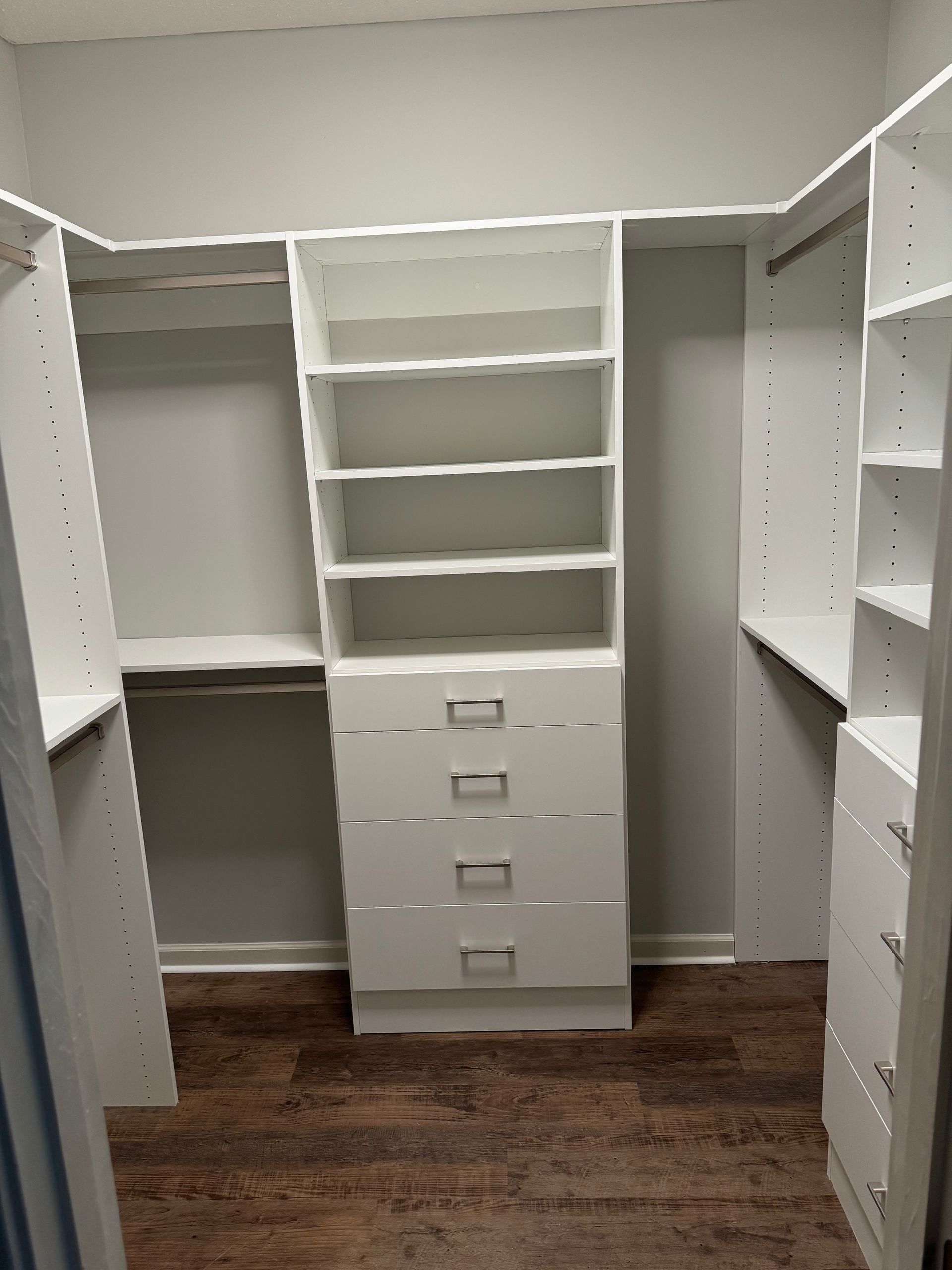White closet organizers in a room with gray walls and brown flooring.