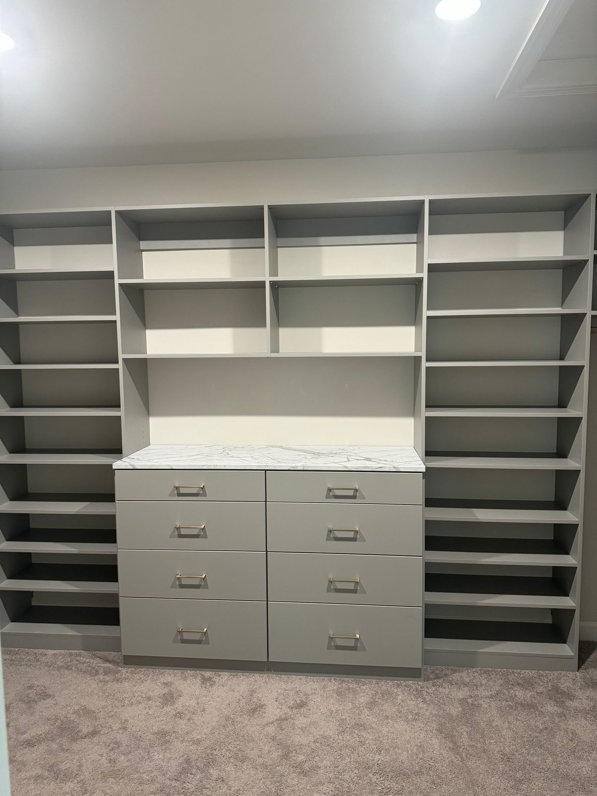 Gray built-in closet with shelves and drawers, set against a neutral wall.