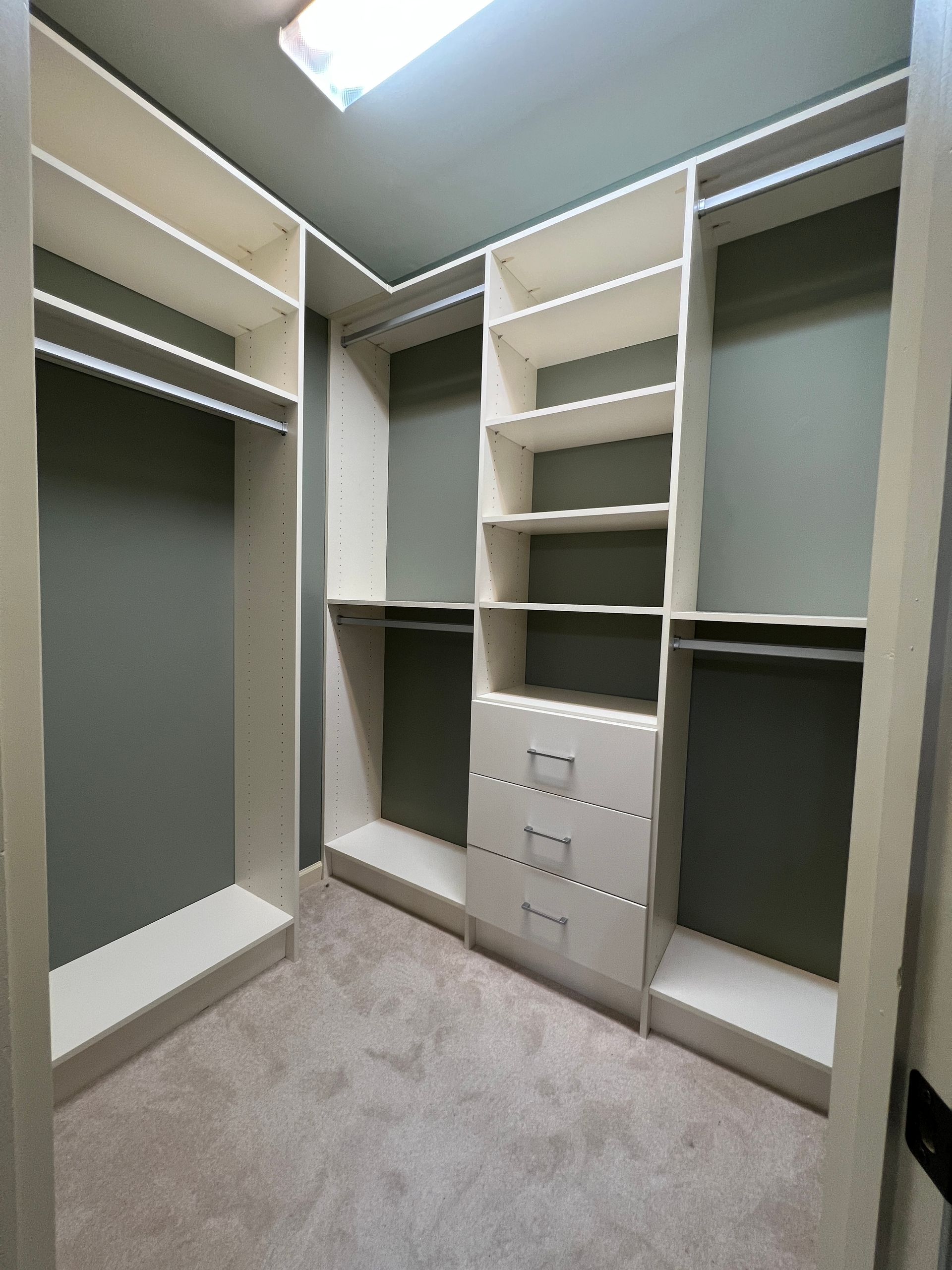 White closet organizers in a room with gray walls and carpet.