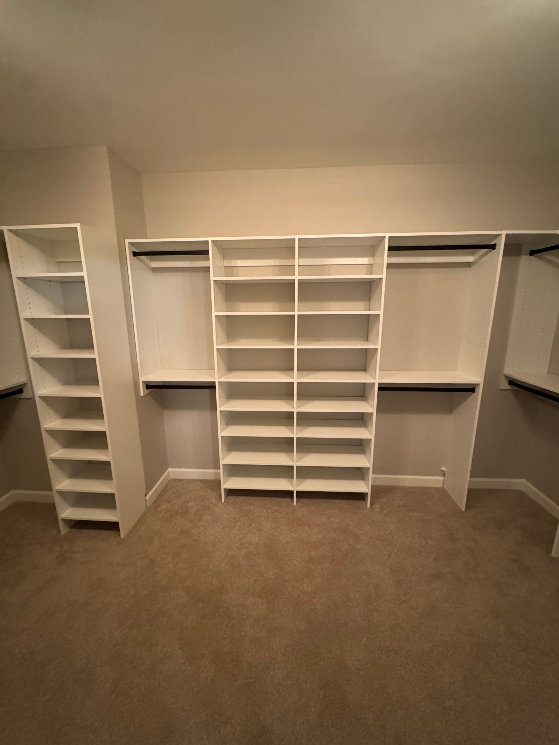 White closet shelving and rods in a carpeted room.