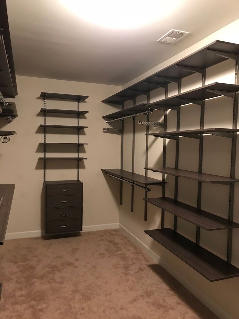A walk in closet with lots of shelves and drawers
