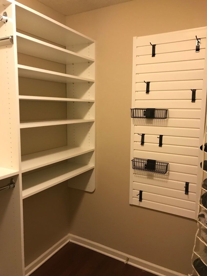 A walk in closet with lots of shelves and a wall mounted shoe rack.