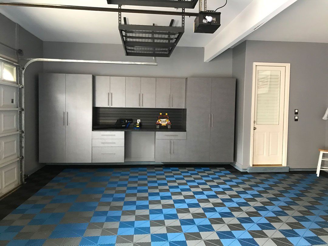 A garage with a blue checkered floor and gray cabinets.