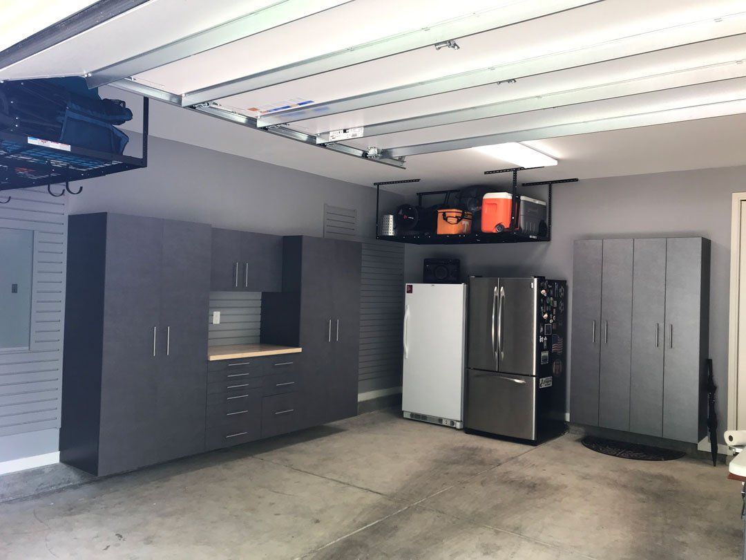 A garage with lots of cabinets , a refrigerator , and a television.