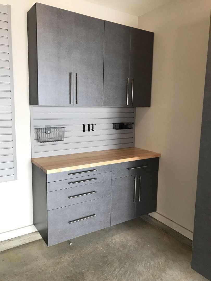 A kitchen with gray cabinets and a wooden counter top.