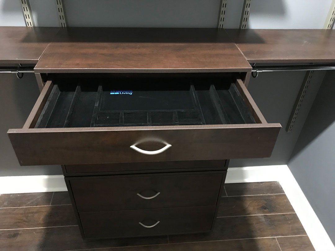 An open drawer in a closet with a black tray in it