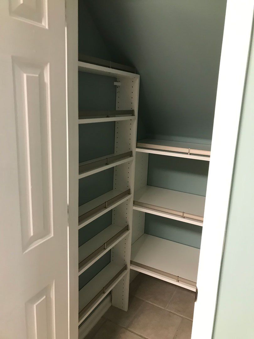 White closet with shelves against a blue-green wall. Door is open.