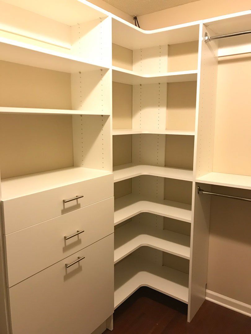 A walk in closet with lots of shelves and drawers
