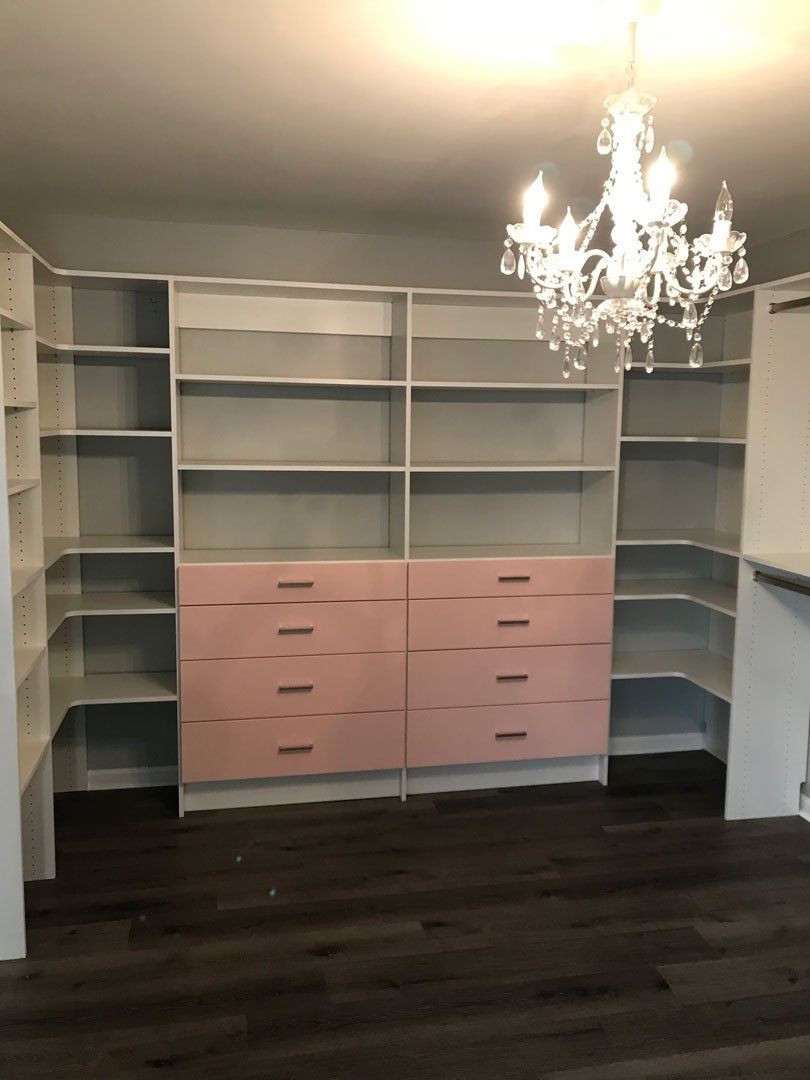 A room with shelves and drawers and a chandelier hanging from the ceiling
