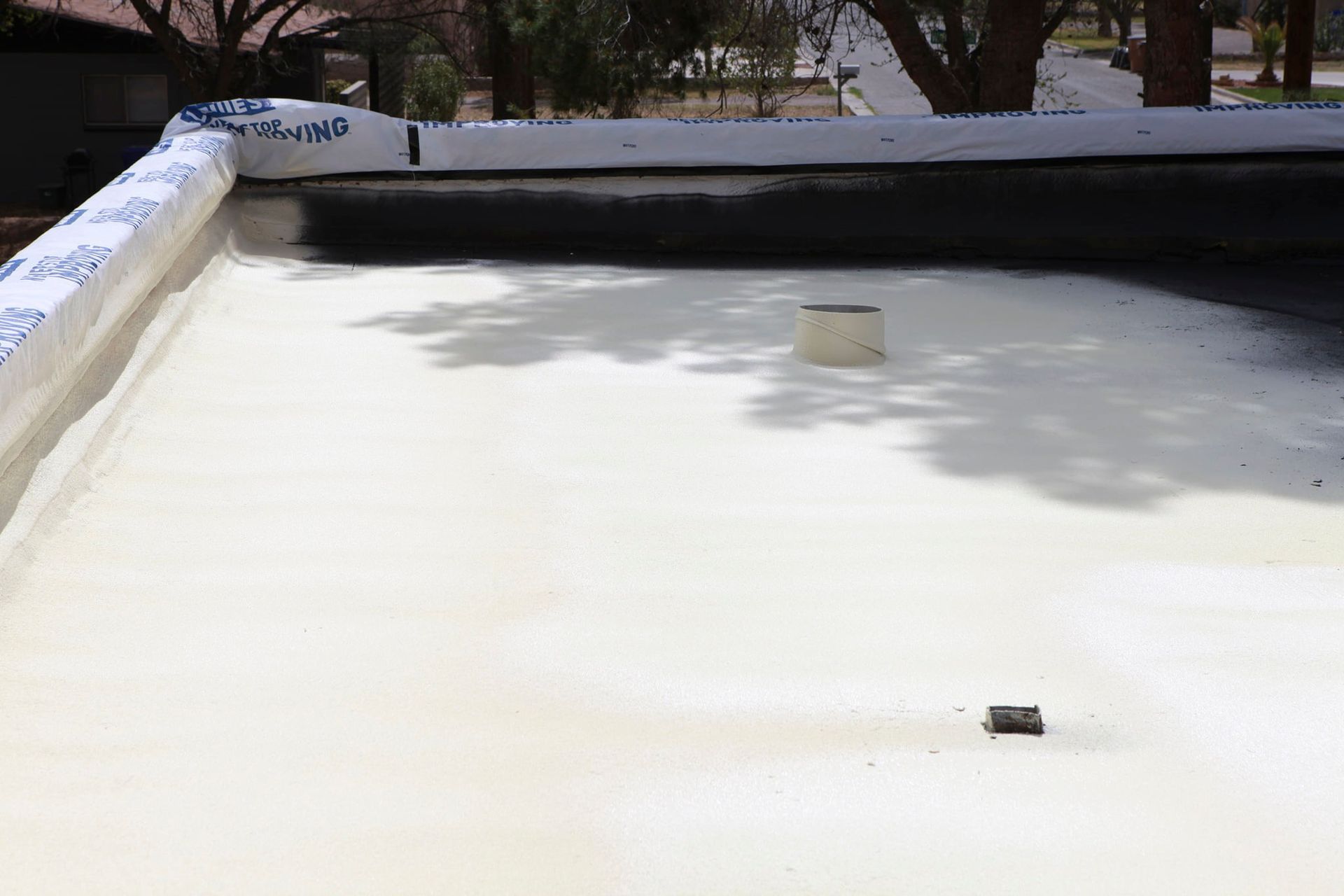 A white roof with a black chimney on top of it.