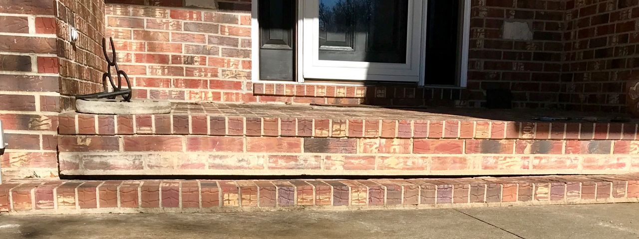 A brick porch with steps leading up to a door.
