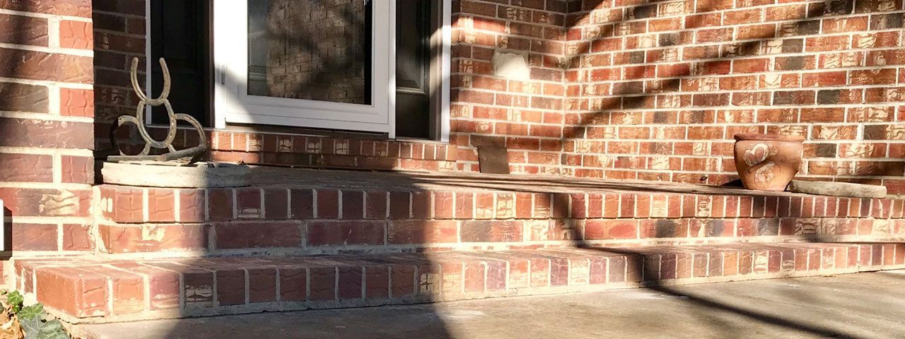 A brick house with a white door and steps.