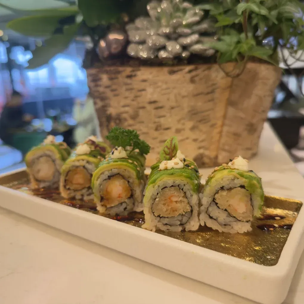 Assortimento di nigiri sushi disposto su un vassoio di ardesia nera con bacchette, salsa di soia e una punta di wasabi.