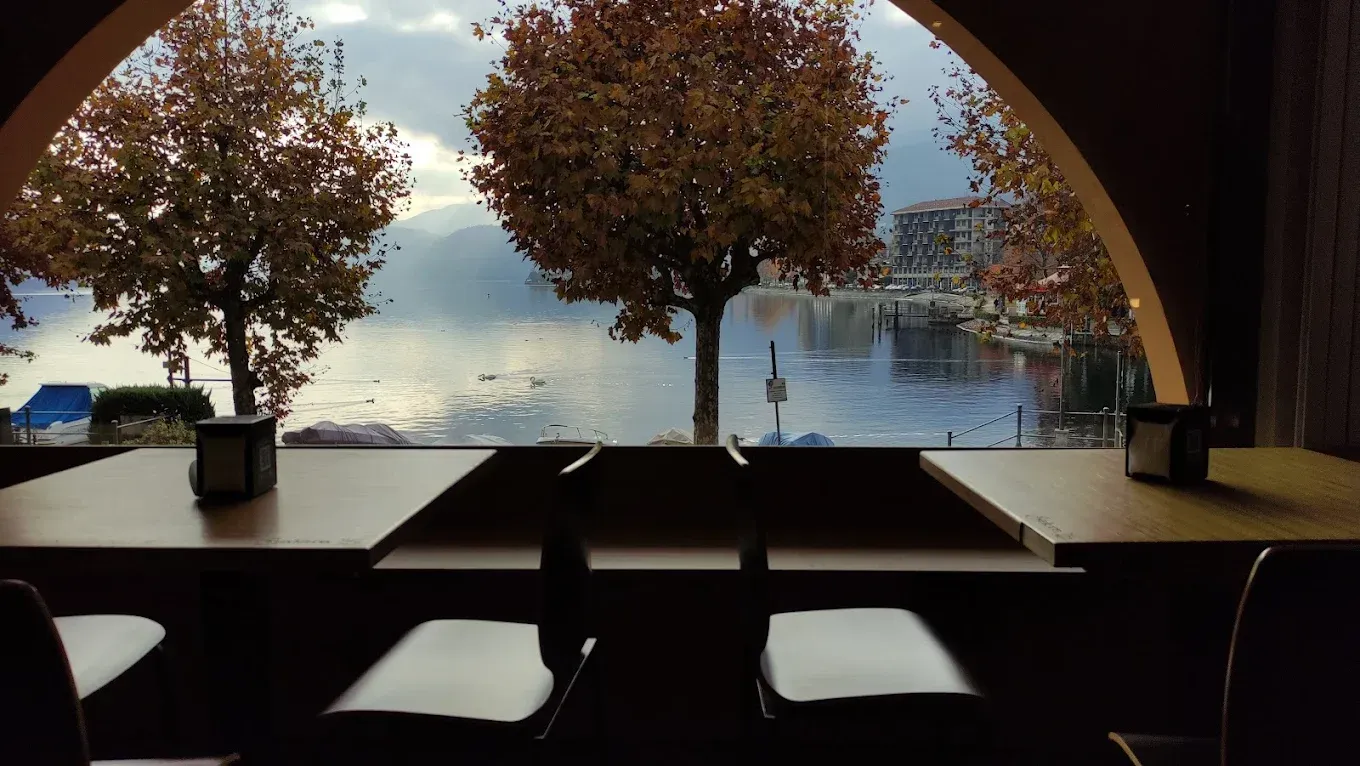 Un piatto di ravioli rotondi, di colore verde, conditi con funghi champignon saltati in padella e scaglie di formaggio bianco a pasta dura.