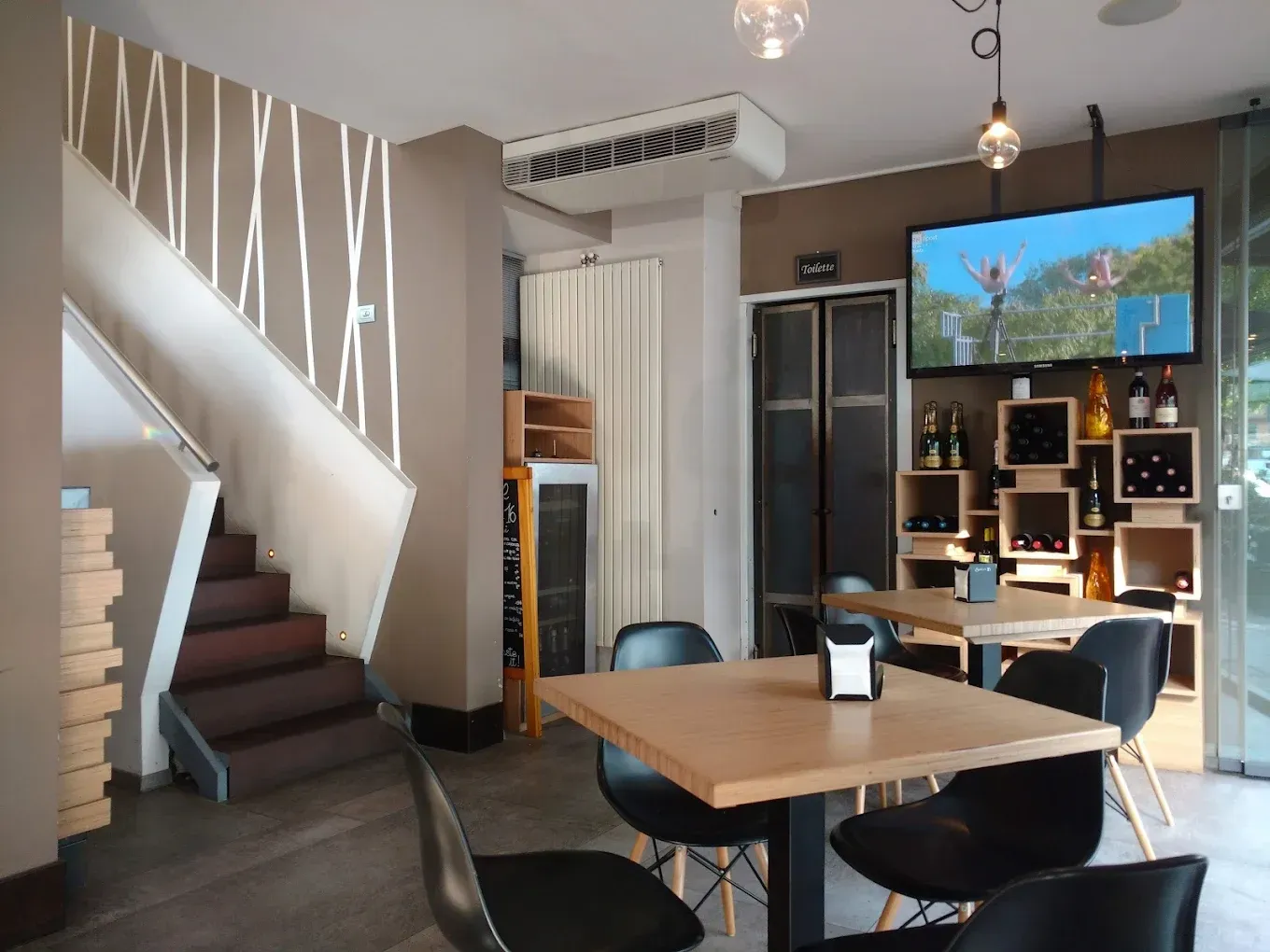 Primo piano di numerose mani che reggono bicchieri pieni di vino bianco per un brindisi in una sala da pranzo festosa e sfocata.