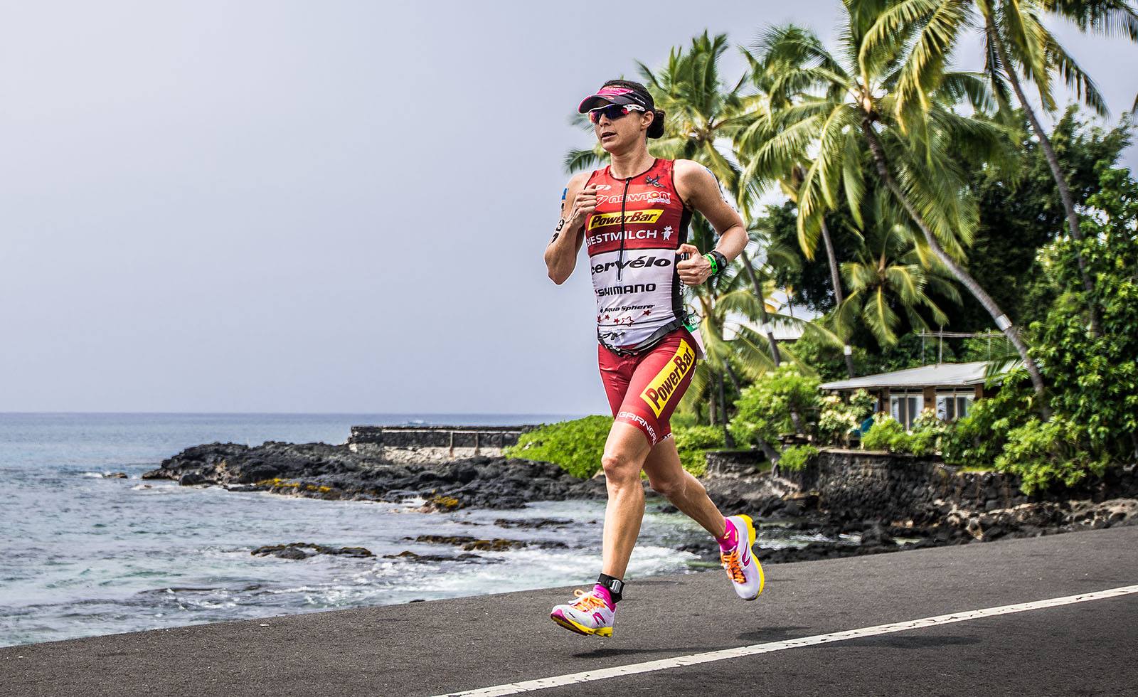 A woman is running on a road near the ocean.