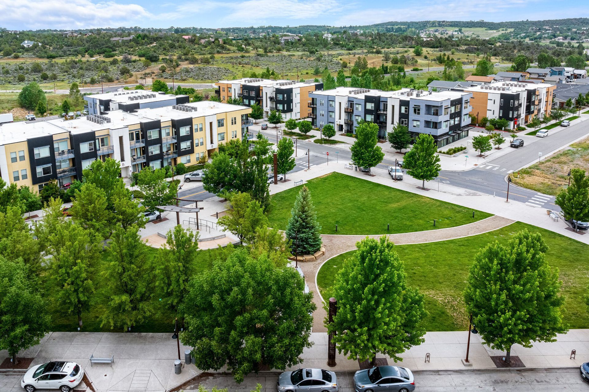 Aerial view of a modern apartment community with a central green park and walkways.