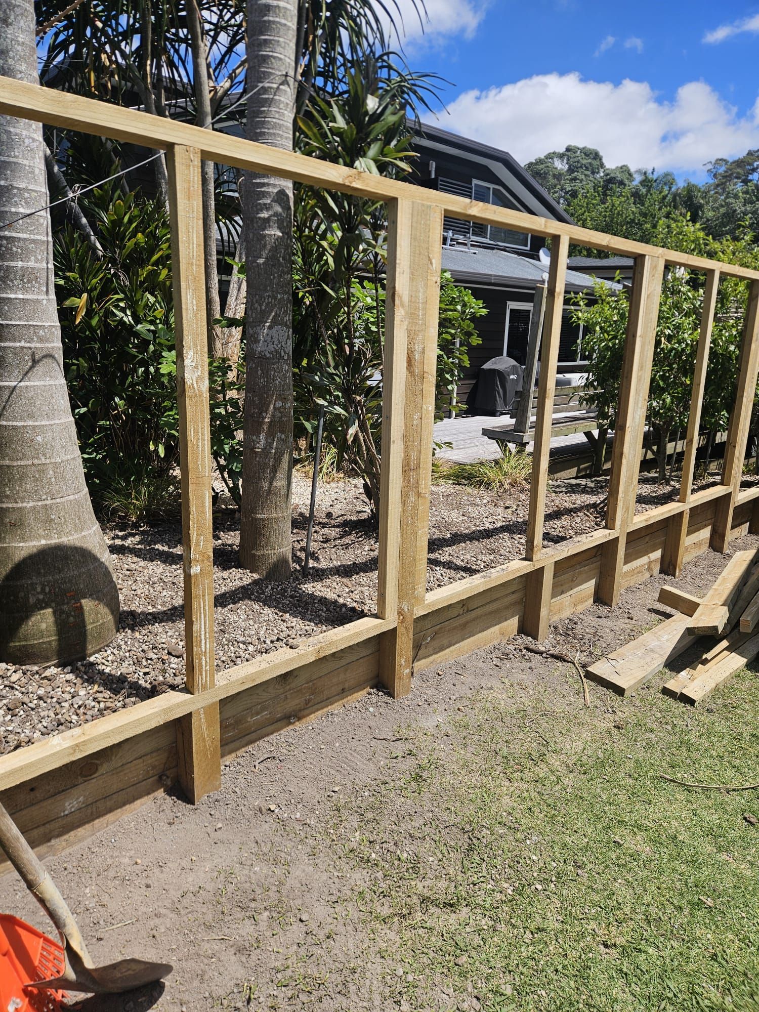 Wooden fence under construction outdoors on a sunny day.