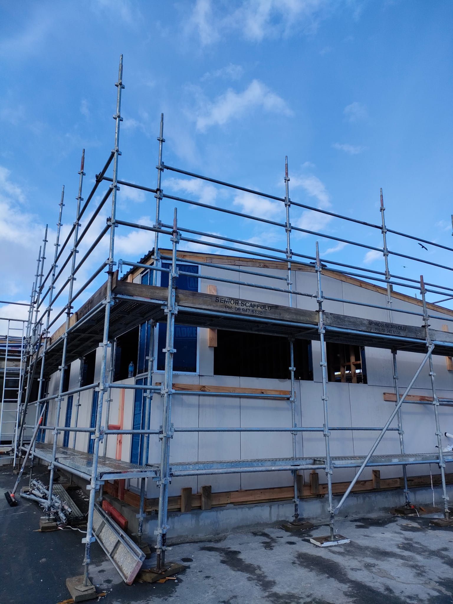 Scaffolding surrounds a building under construction, blue sky background.