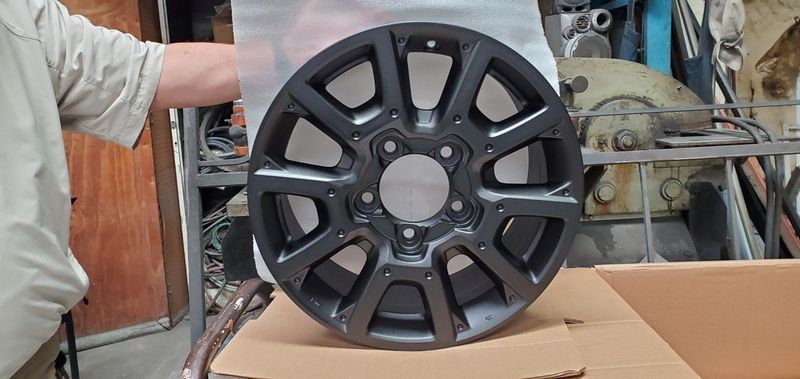 A Man is Holding a Black Wheel on Top of a Cardboard Box