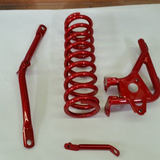 A Red Coil Spring is Sitting on a White Surface