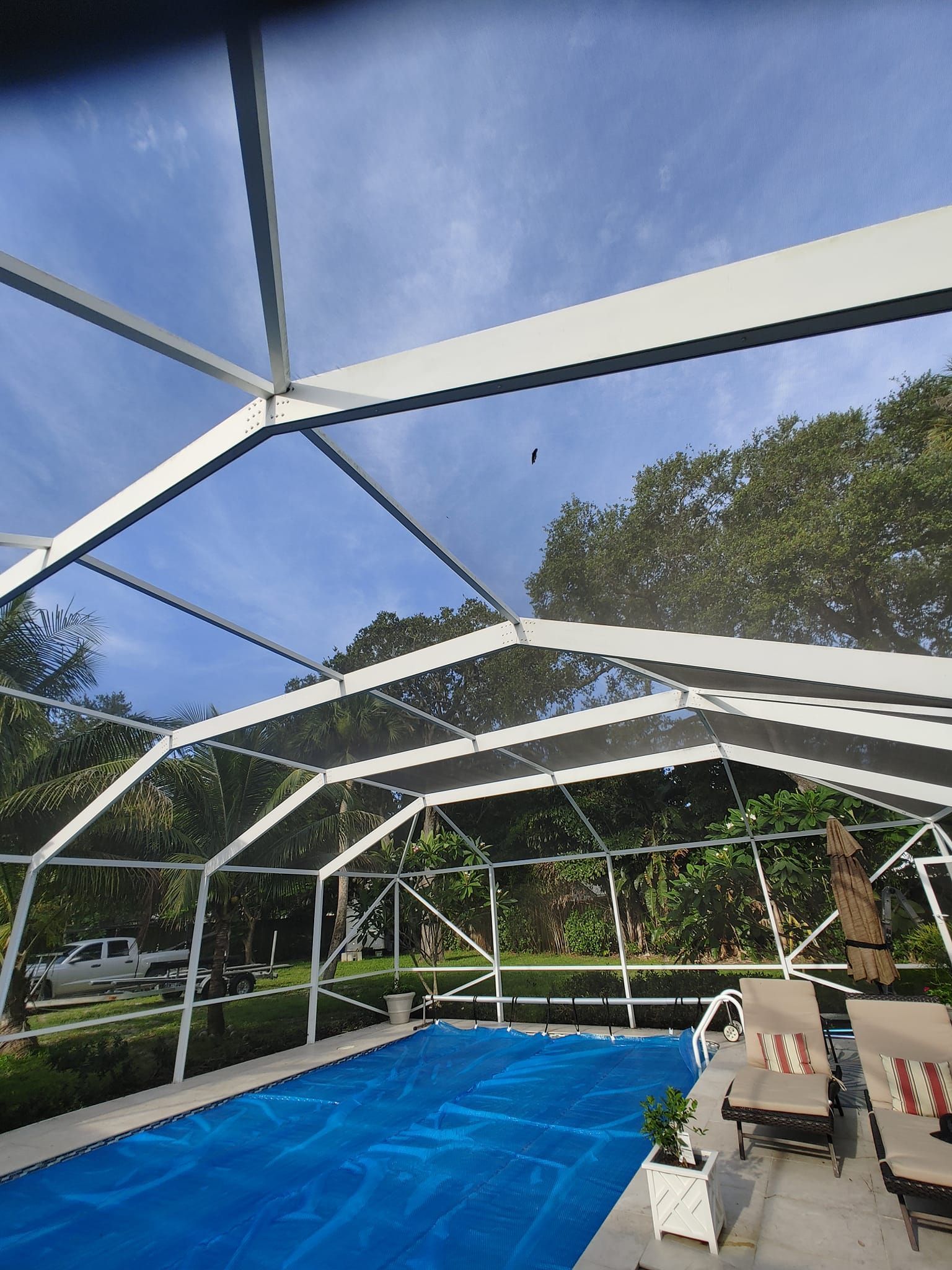 A swimming pool with a screened in area and a blue cover.