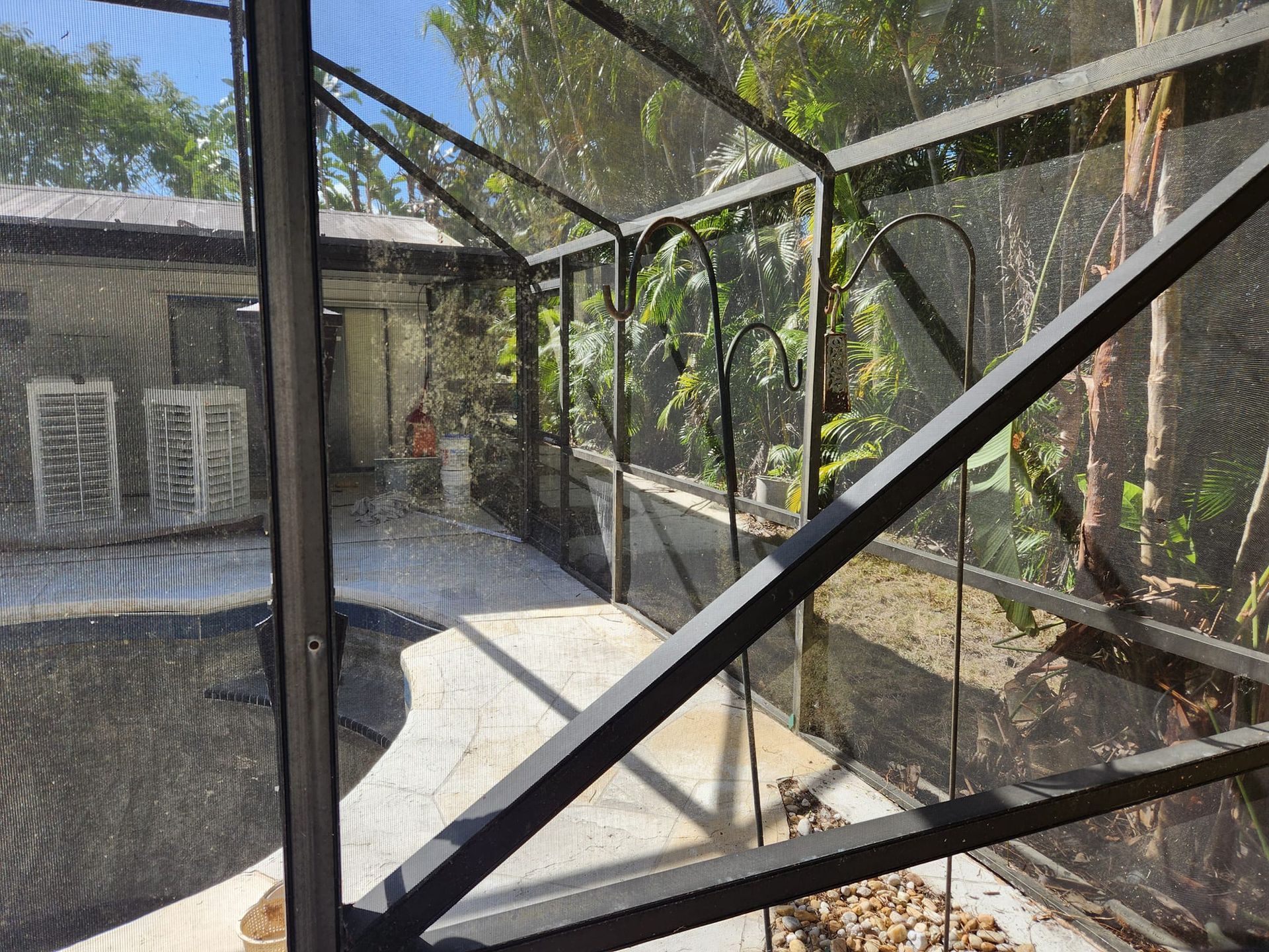 A view of a patio through a screened in area of a house.