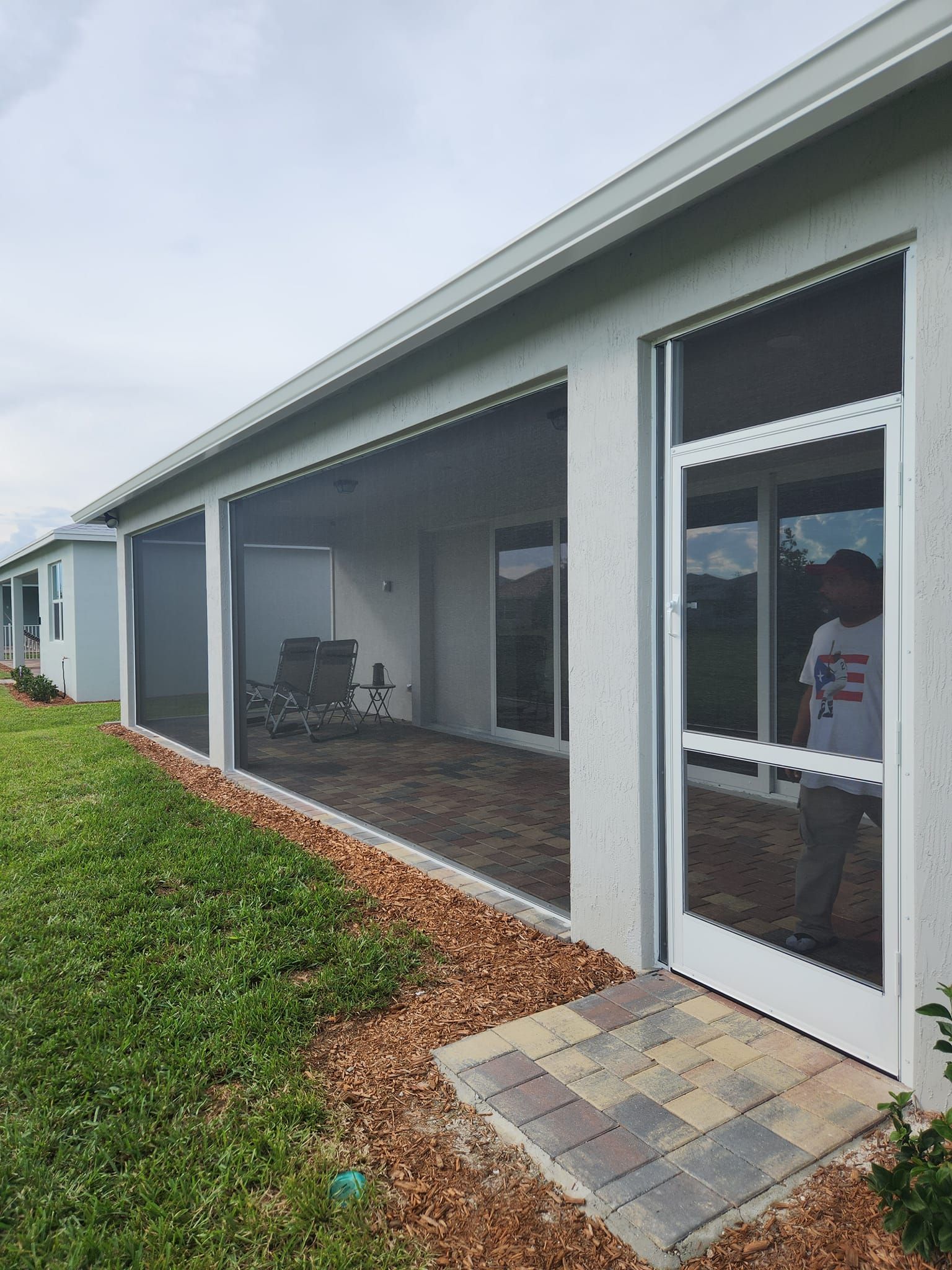 A man is standing in front of a screened in porch.