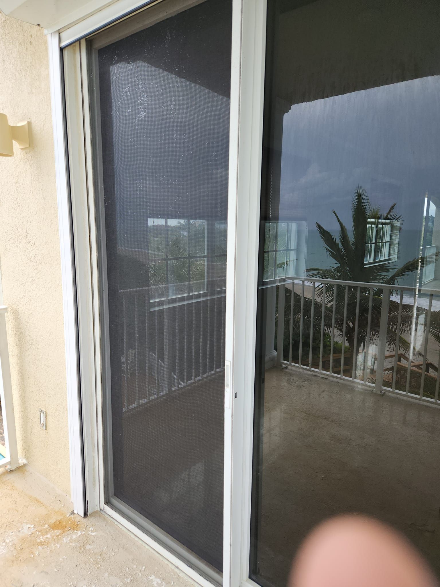 A person is standing in front of a sliding glass door with a screen on it.