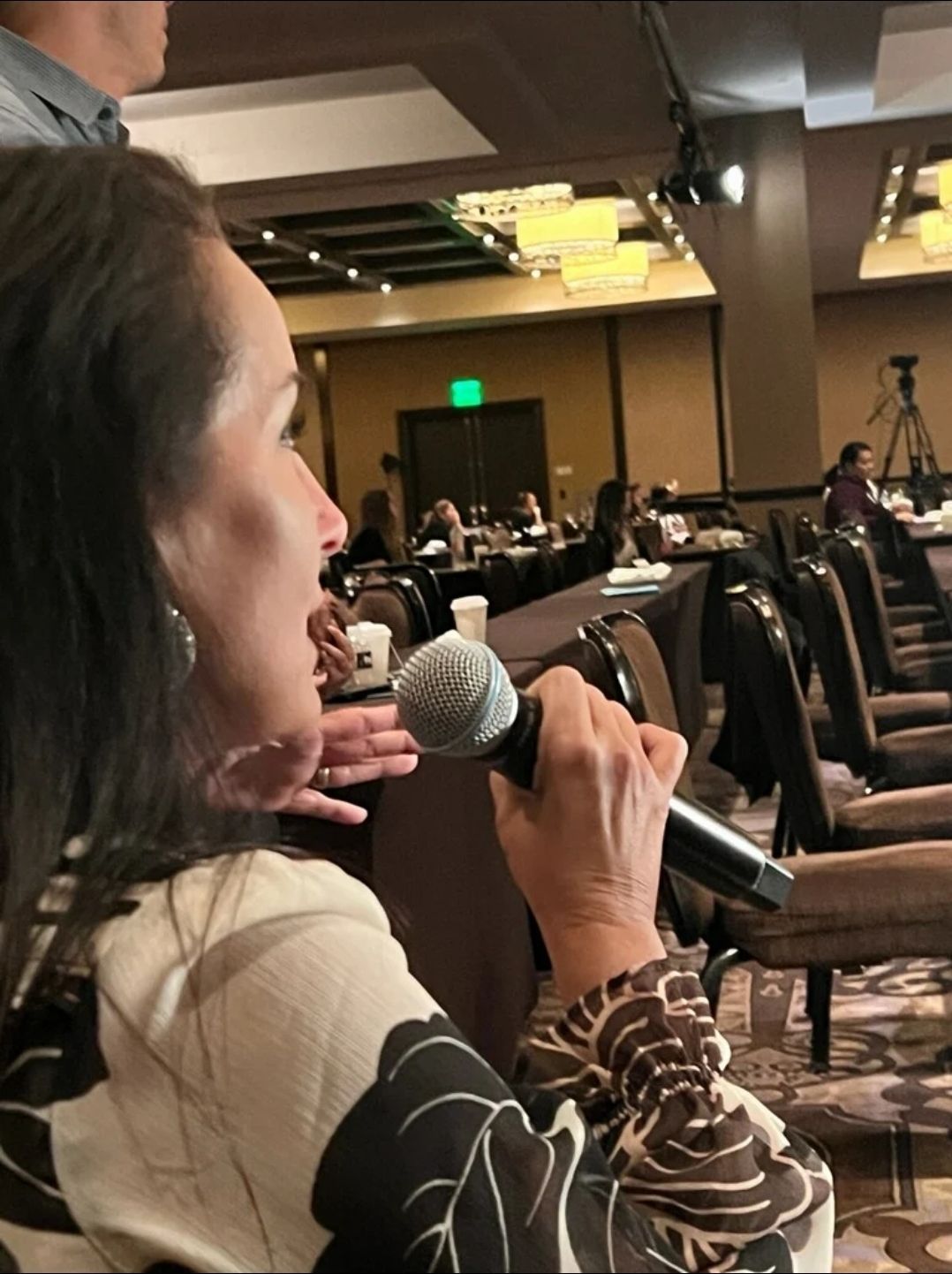 Woman speaking into a microphone at a conference.