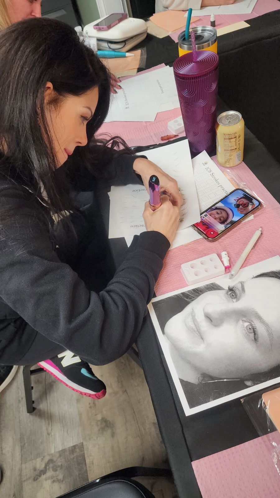 Woman leaning over a desk, drawing on paper, alongside a photo