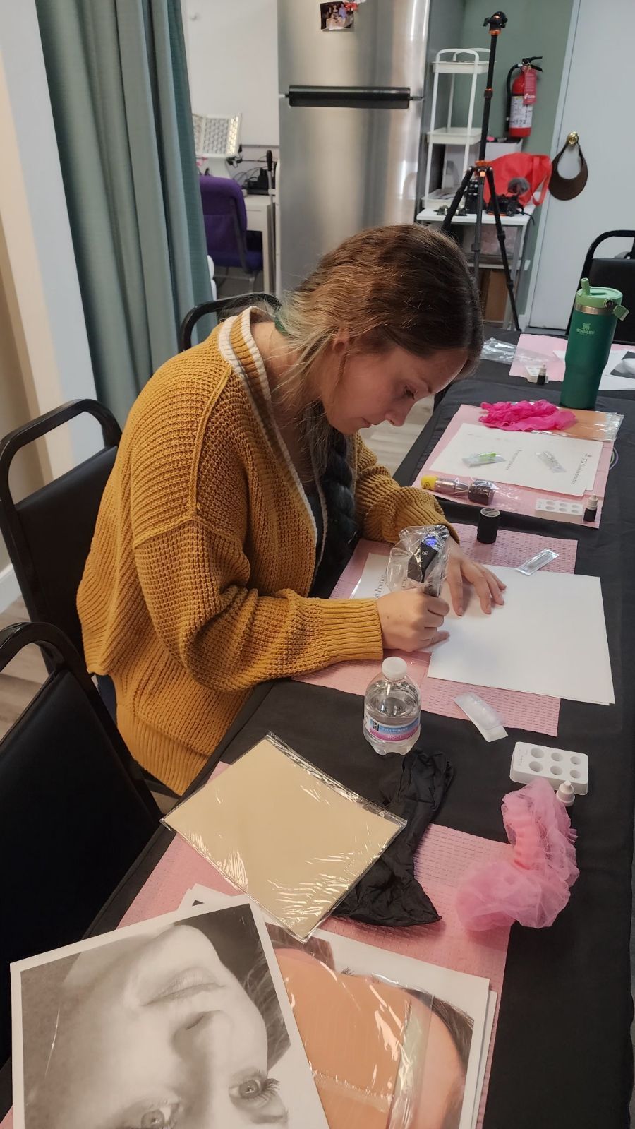 Woman in yellow sweater sits at a table, drawing.