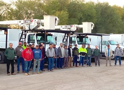 a group of men are standing in front of a row of trucks .