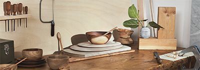 A wooden table with plates , bowls , and a plant on it.