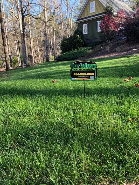 A sign in the grass in front of a house.