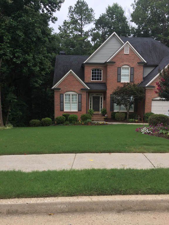A large brick house with a lush green lawn in front of it