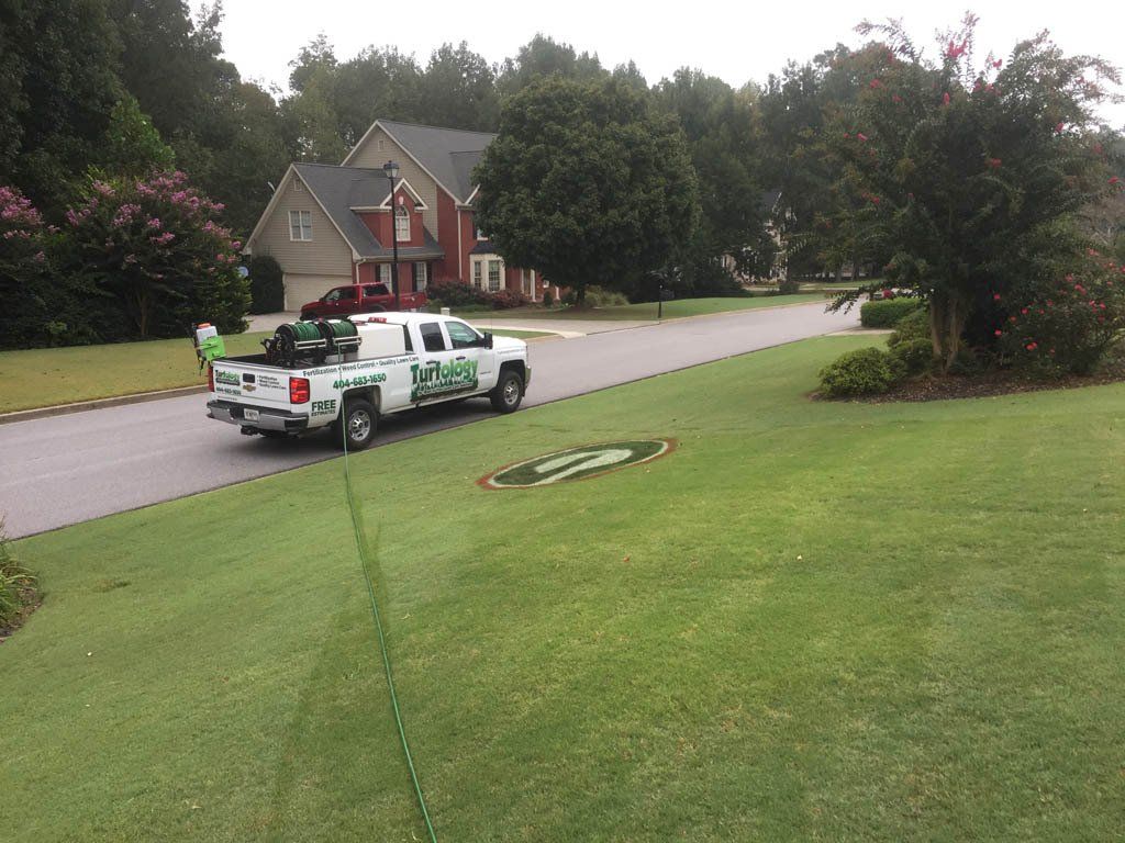 A lawn care truck is parked in front of a house