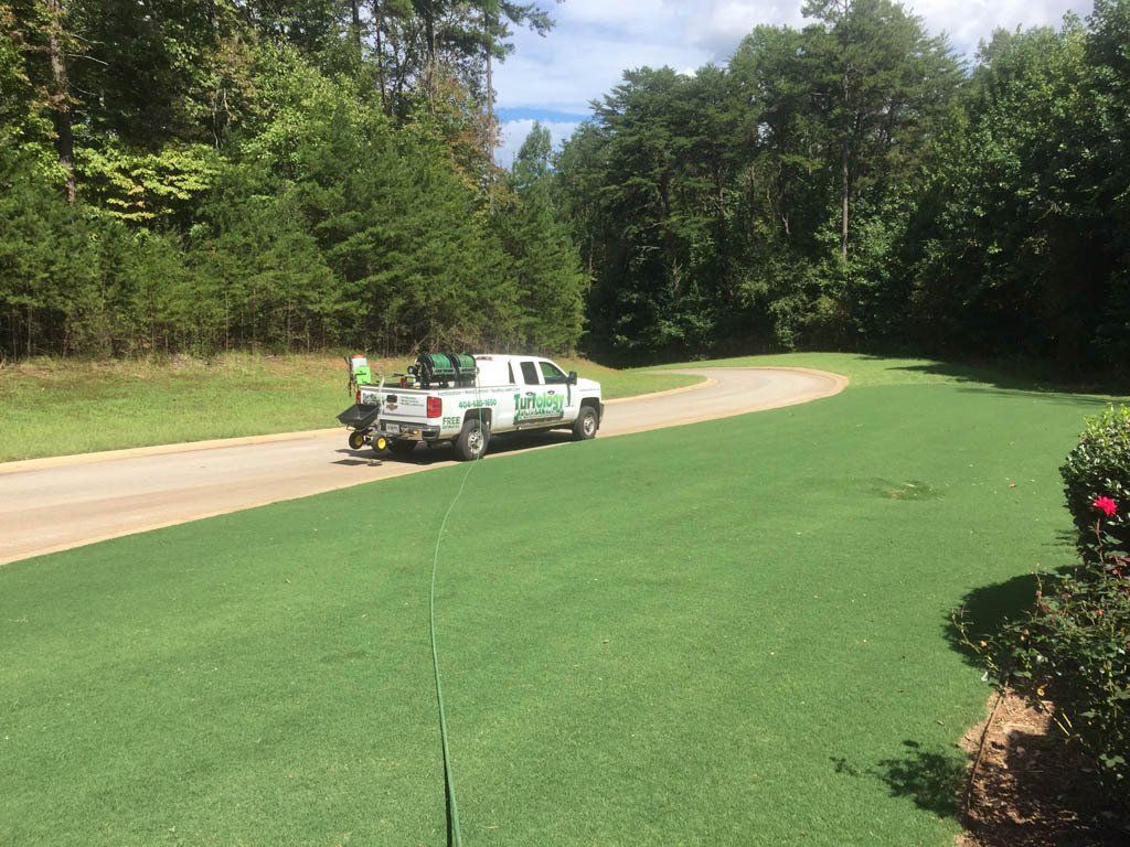 A truck is parked on the side of a road next to a golf course.
