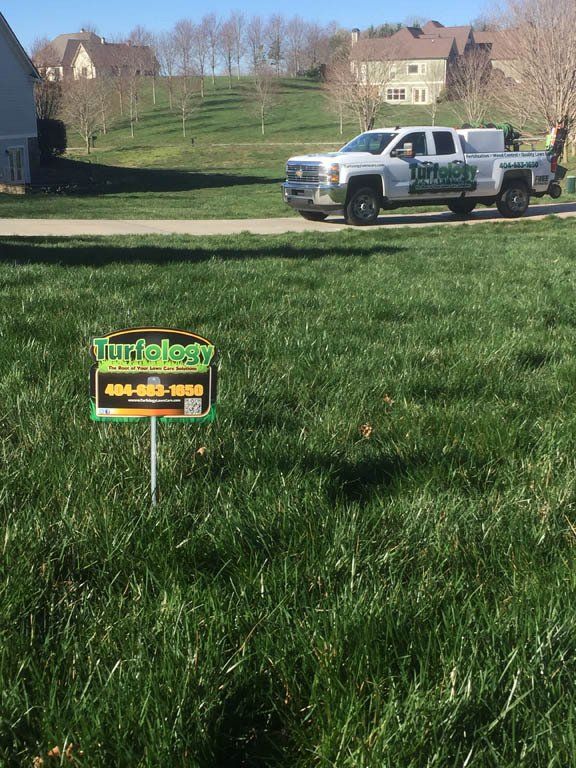 A truck is parked in the grass next to a sign.