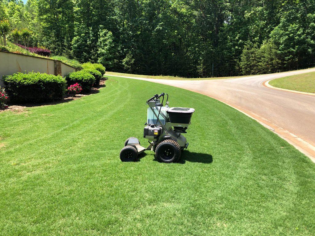 A lawn mower is sitting on top of a lush green lawn next to a road.