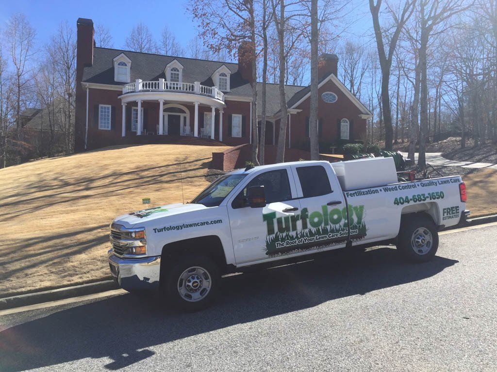 A white truck is parked in front of a large house.