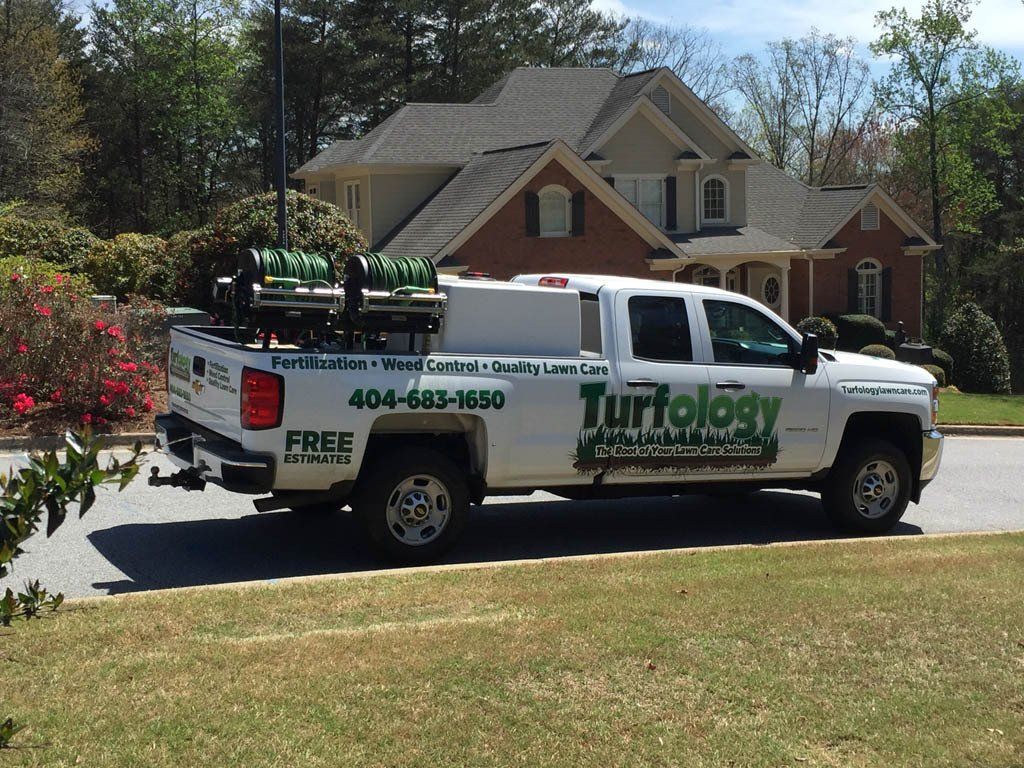 A turfology truck is parked in front of a house