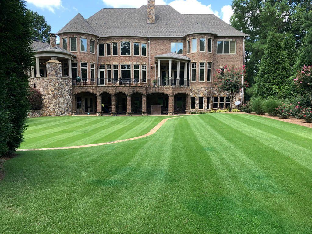 A large brick house with a lush green lawn in front of it.