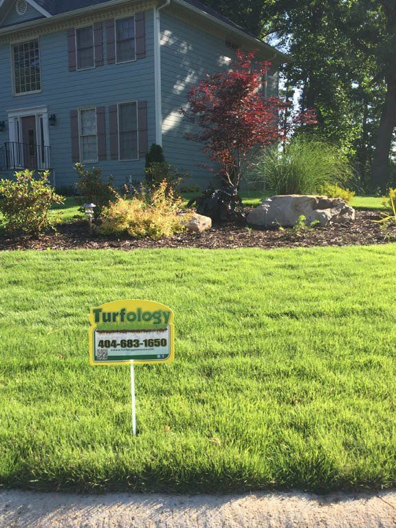A sign in front of a house that says turfology