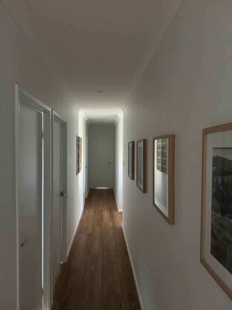 A long hallway with wooden floors and white walls.