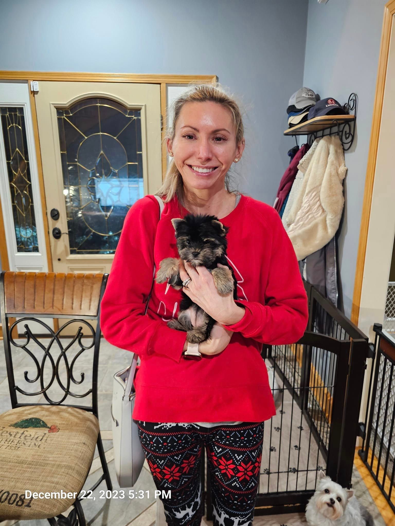 A woman is holding a puppy in her arms in a living room.